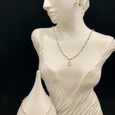 a white mannequin with a necklace and earrings on it's head, against a black background