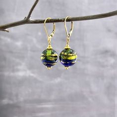 ✦These brilliant Italian Venetian Murano beads have the Serale style with round Venetian glass beads that have exterior gold bands and an ombre peridot green from top to a navy blue bottom. The beads are adorned with gold daisy spacers. Bead size is 12mm. ✦The ear wires are sturdy 14k gold-filled lever backs.  Also available with French hook ear wires - please leave a note at check out if you want French hook ear wires in place of leverback. Earring length approximately 1.5 inches.   ✦Matching pendant necklace available. Earrings and necklace can be purchased separately or as a set. Please select purchase options at check out. ✦Your jewelry will be packaged in a beautiful and reusable organza bag. All items will be placed in the same organza bag. If you need a separate bag for each item, p Murano Glass Earrings, Diy Jewelry Projects, Blue Green Gold, Peridot Green, Leverback Earrings, Jewelry Card, Venetian Glass, Navy Gold, Glass Earrings