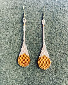 a pair of yellow and white beaded earrings on top of a gray countertop