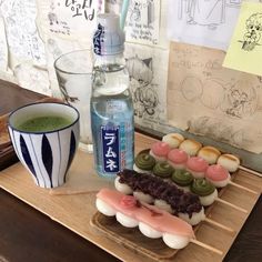 an assortment of sushi on a wooden tray next to a cup of green tea