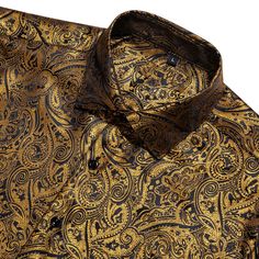 Add a touch of luxury to your wardrobe with the Black and Gold Paisley Silk Short Sleeve Shirt. Expertly crafted from premium silk, this shirt offers an exceptionally smooth and comfortable feel, making it perfect for any sophisticated occasion. The elegant black fabric is beautifully enhanced by a stunning gold paisley pattern, creating a striking visual contrast that exudes opulence and style. Perfect for upscale casual events, summer gatherings, or evening outings, this short sleeve shirt sea Luxury Long Sleeve Satin Shirt, Elegant Silk Top For Business, Elegant Silk Shirt For Formal Occasions, Luxury Satin Formal Shirt, Luxury Collared Tops For Evening, Luxury Satin Tops, Classic Gold Shirt For Formal Occasions, Classic Gold Silk Blouse, Elegant Silk Business Shirt