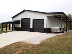 a white and black garage sitting on top of a grass covered field next to a building