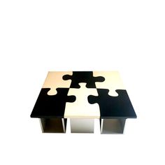 a black and white coffee table with four puzzle pieces on it's sides, sitting against a white background