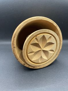 a wooden cup with a flower design on the top and bottom, sitting on a gray surface