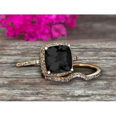 a black and white diamond ring on top of a wooden table with pink flowers in the background