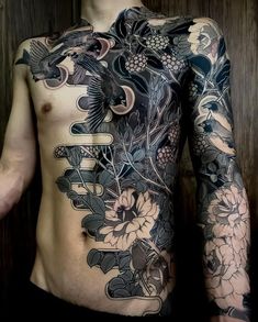 a man with tattoos on his back and chest is standing in front of a wooden wall