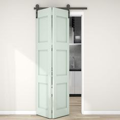 an open green door in front of a white wall and wooden floor with a kitchen behind it