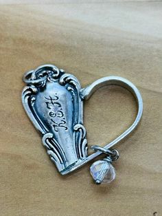 a silver heart shaped keychain with a small crystal bead hanging from it's side