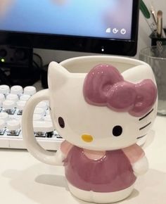 a hello kitty coffee mug sitting in front of a computer