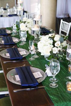 the table is set with white flowers and blue napkins