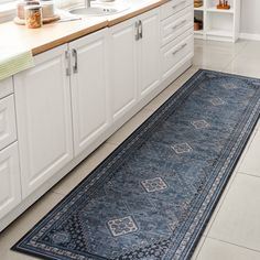 a large blue rug is in the middle of a kitchen with white cabinets and counters