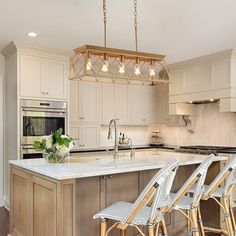 a kitchen with white cabinets and wooden stools in front of an island that has four bar stools on it