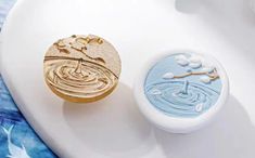 two decorative soaps sitting on top of a white plate with blue and gold designs