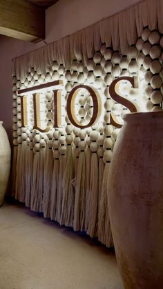 two large vases sitting in front of a lit up sign that says tuos