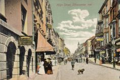 an old postcard shows people walking down the street