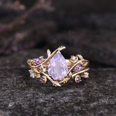 a ring with an amethorate and pink stones on it sitting on top of a rock