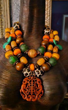 This stunning triple strand oversized beaded statement necklace will look fabulous paired with animal prints or authentic African prints. Components include zebu bone, wood, African recycled glass, quartz teardrop beads, copper daisy spacers, dark brown wood rondelles, bronze rhinestone rondelles, hand painted African glass beads, an Ethiopian copper bead and gold tone tribal spacers. A hand carved rust colored Asian pendant is the focal point which measures 2.5" x 2.5". I would describe this as a medium weight, but please remember that weight is subjective. Adjusts from 17-20" and I can add more links if requested. Silver tone hardware and a lobster claw clasp. From the Atelier of Kat Kouture. Statement Beaded Necklace With Dangling Beads, Traditional Luxury Necklace With Large Beads, Luxury Traditional Necklace With Large Beads, Luxury Adjustable Beaded Statement Necklaces, Luxury Jeweled Statement Beaded Necklaces, Luxury Statement Beaded Necklace, Luxury Hand-strung Bohemian Beaded Necklaces, Luxury Round Beads Necklaces For Festivals, Luxury Round Bead Necklaces For Festivals