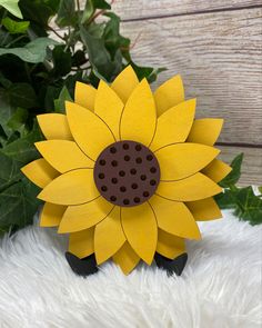 a wooden sunflower sitting on top of a white furnishing next to a plant