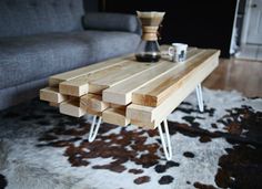 a coffee table made out of wood blocks on top of a cowhide area rug