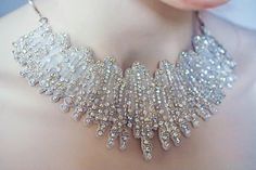 a close up of a woman's neck wearing a silver necklace with crystal beads