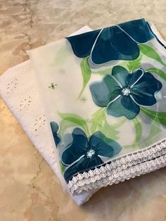 two napkins with blue flowers on them sitting on a marble counter top next to each other