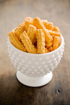 a white bowl filled with cheetos on top of a wooden table