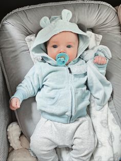 a baby in a stroller wearing a blue hoodie and pacifier on his face