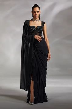 Black georgette pre-draped saree with ruffle details near the slit. Comes with padded corset blouse.
Component: 2
Pattern: Embroidery
Neckline: Sweetheart
Sleeve Type: Sleeveless
Fabric: Corset: Satin and Tulle, Saree: Georgette
Color: Black
Other Details: 
Attached lining
Weight approx (in kg) : 1.2
Note: The neckpiece worn by the model is not for sale
Occasion: Sangeet - Aza Fashions Drape Saree Designer 2023, Corset Sari Blouses, Black Corset Blouse, Sweetheart Neckline Blouse Pattern, Black Cocktail Saree, Corset Sari, Corset Saree Blouse Design, Black Drape Saree, Corset Outfit Indian