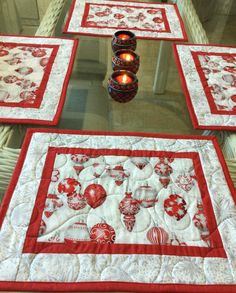 four quilted place mats with candles on them in front of a glass table top