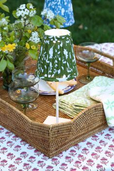 the table is set with two lamps, plates and flowers in vases on it