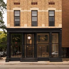 an empty street in front of a brick building with glass doors and windows on both sides