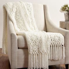 a white crocheted blanket sitting on top of a chair