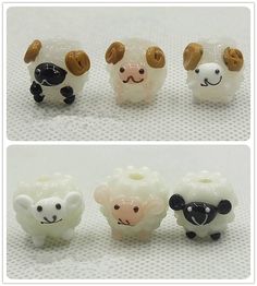 there are four small sheep figurines in the same row and one is white with brown ears