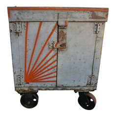 an old metal box sitting on wheels with the sun painted on it's side