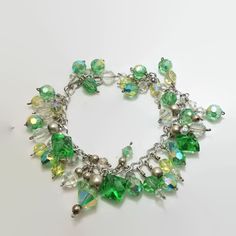 This is a sterling silver cha cha bracelet with tons of individually wire wrapped clear and green crystal beads. The square green beads are actually vintage glass buttons. There are also several round sterling silver beads. The bracelet measures 7"l. and is finished with a spring ring clasp. No damage.