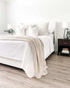 a bedroom with white bedding and pillows on the bed, along with two nightstands