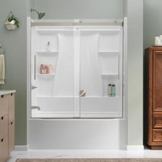 a bath tub sitting inside of a bathroom next to a wooden dresser and cabinet with drawers