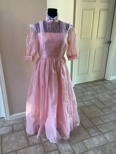 This nice vintage 70s pink & white Cottagecore like Prairie high collar pinafore see thru like maxi ruffle dress comes to you in a size M. It is made of a Swiss dot material with ruffles and high collar- Gunne Sax like. Inside dress is a pink slip fitted. And then the dress is a separate piece. Measurements r as follows-underarm to underarm is 18 inches. Waist is 14 inches. 47 1/2 inches underarm to bottom of dress. Satin slip fitted is what was measured. Pink Vintage Dress For Daywear, Elegant Pink Victorian Spring Dress, Elegant Pink Victorian Dress For Spring, Vintage Prairie Dress Maxi Length, Feminine Spring Victorian Daywear Dress, Spring Victorian Dress For Party, Full-length Dresses For Vintage Events, Pink Fitted Victorian Dress For Spring, Pink Victorian Dress With Lace Trim