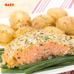 a white plate topped with green beans and salmon covered in seasoning next to potatoes