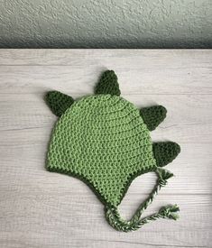 a crocheted green hat with an ear flap and ears attached to the brim