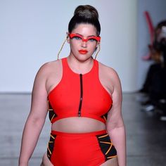 a woman in a red swimsuit walks down the runway