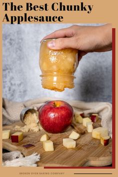 a person is holding a jar over an apple on a cutting board with chopped apples