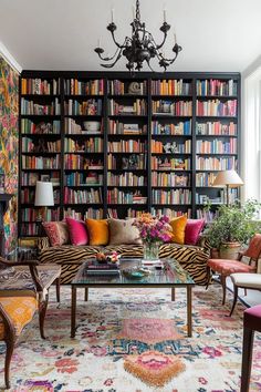 a living room filled with lots of furniture and bookshelves covered in colorful books