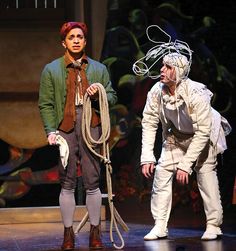 two men dressed in period costumes on stage with ropes attached to their heads and hands