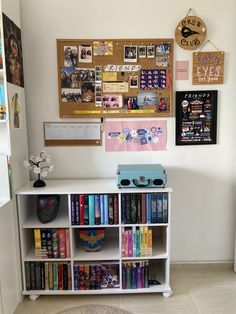 a bookshelf filled with lots of books next to a wall covered in pictures