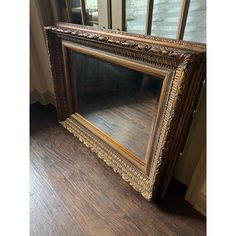 an old wooden framed mirror sitting on top of a hard wood floor