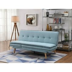 a blue couch sitting on top of a wooden floor next to a book shelf filled with books