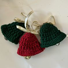 two crocheted christmas bells hanging from a ribbon