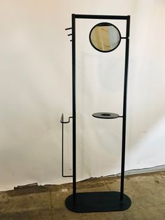 a black stand with a round mirror on it's side and a metal rod