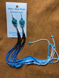 12 inch long earrings, created with size 11/0 seed beads. They have 5 tassels each longer than the last, there is a gem stone on the end of each tassel. There is a silver plated cone at the top with a decorative bead (turtle, heart) and 2 more gem stones.

- These earrings are made with black, dark blue, light blue and white seed beads.
- Each earring has a turquoise heshi bead is on the end of each tassel (5 per earring).
- Each earring also has a blue turtle and 2 more heshi beads on the top. Bead Turtle, Blue Turtle, Decorative Beads, Long Tassel Earrings, Dusters, Gem Stones, Gem Stone, Tassel Earrings, Long Earrings